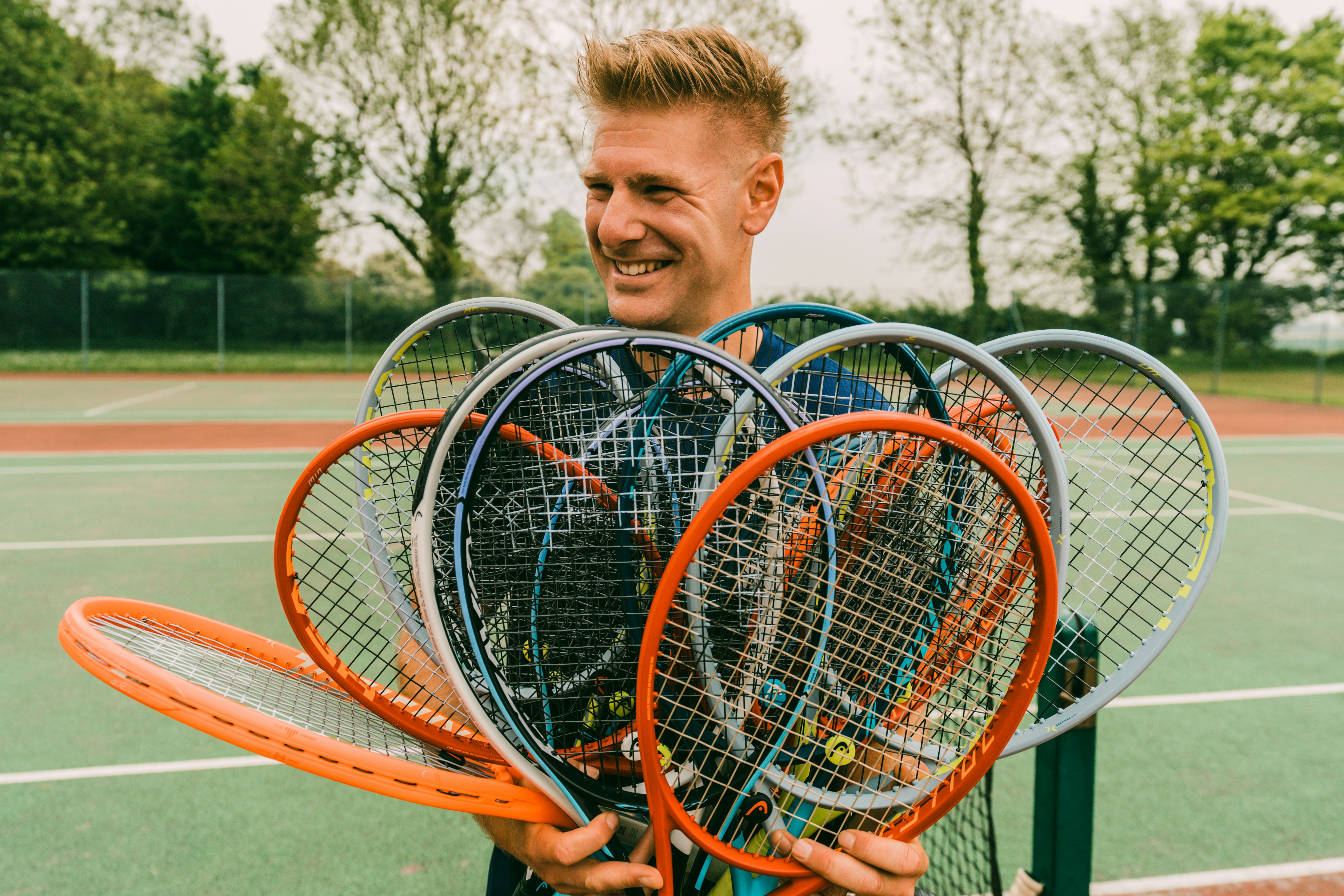 boy in blue polo shirt holding red and black tennis racket